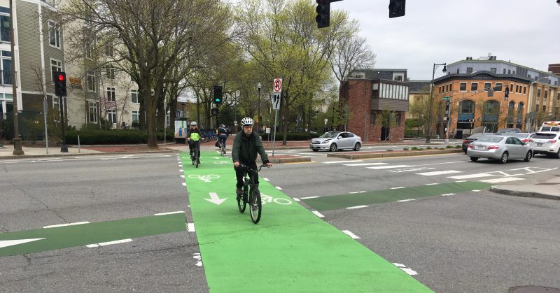 Bicyclists on the Somerville Community Path cross Massachusetts Avenue in North Cambridge in May 2019.