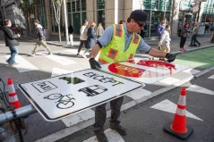 An city worker prepares new signage on Market Street in downtown San Francisco in advance of the street's closure to private cars. Courtesy of SFMTA.