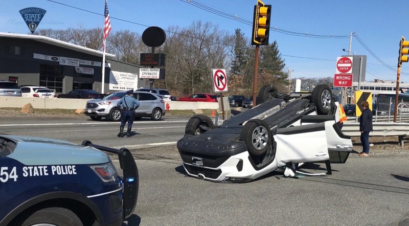 An uninjured driver stands next to the SUV she flipped over while driving on Route 1 in Peabody on March 18, 2020. Photo courtesy of the Massachusetts State Police.