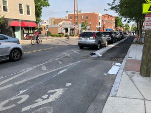 A bike rider rolls past a new protected bike lane under construction on Hampshire Street in Inman Square.