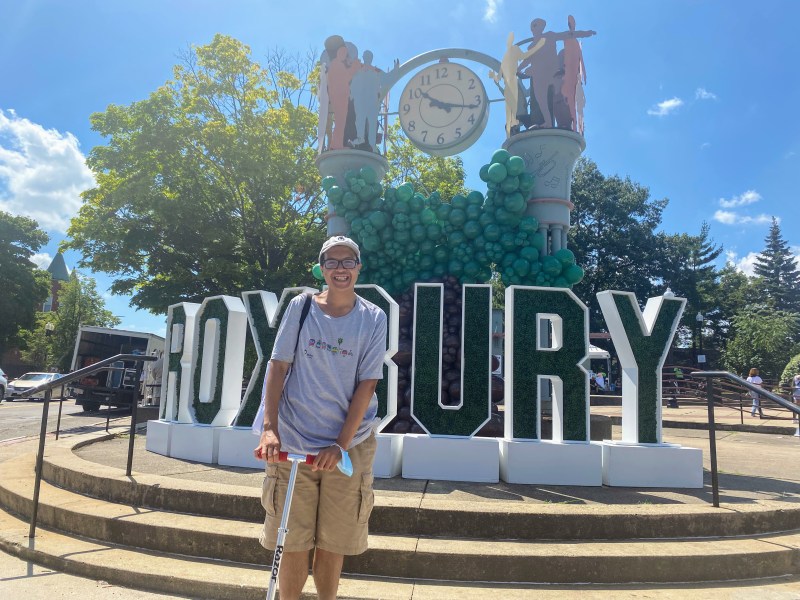 Kenny Uong, who traveled to the event by train early Saturday morning from Providence, Rhode Island, poses with his scooter in front of the large Roxbury sign at the intersection of Dudley Street and Blue Hill Avenue welcoming folks to the Open Streets event. “I really love Open Streets -- it's a really great way to explore the neighborhoods in a car-free way,” said Uong.