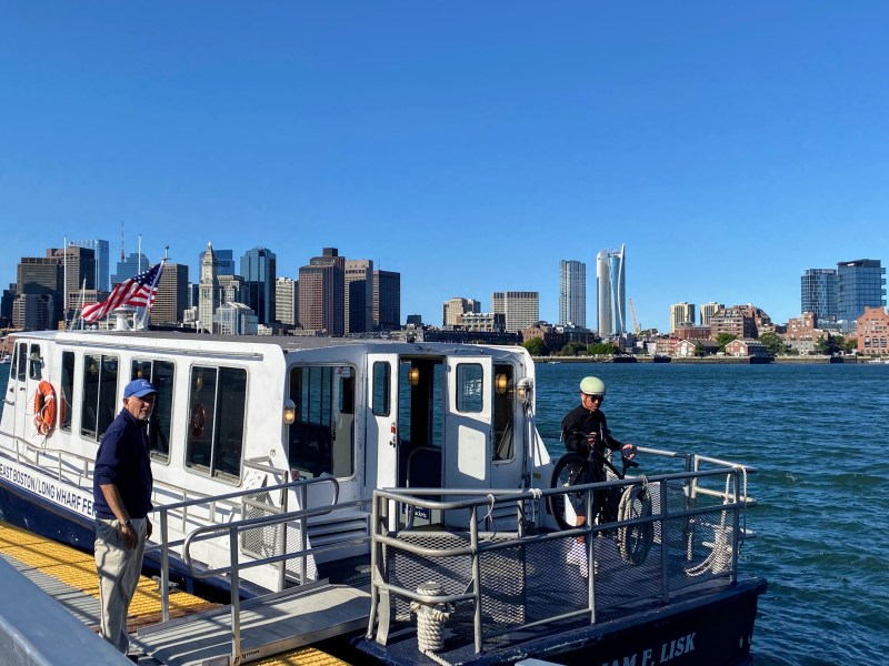 Lewis Mall, East Boston: A ferry attendant waits for a bicyclist to wheel his bike onboard before loading the removable metal ramp back on the ferry this morning.